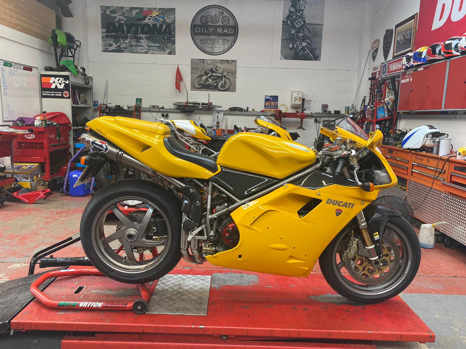 A yellow Ducati superbike on the red lift inside the Autocraft workshop