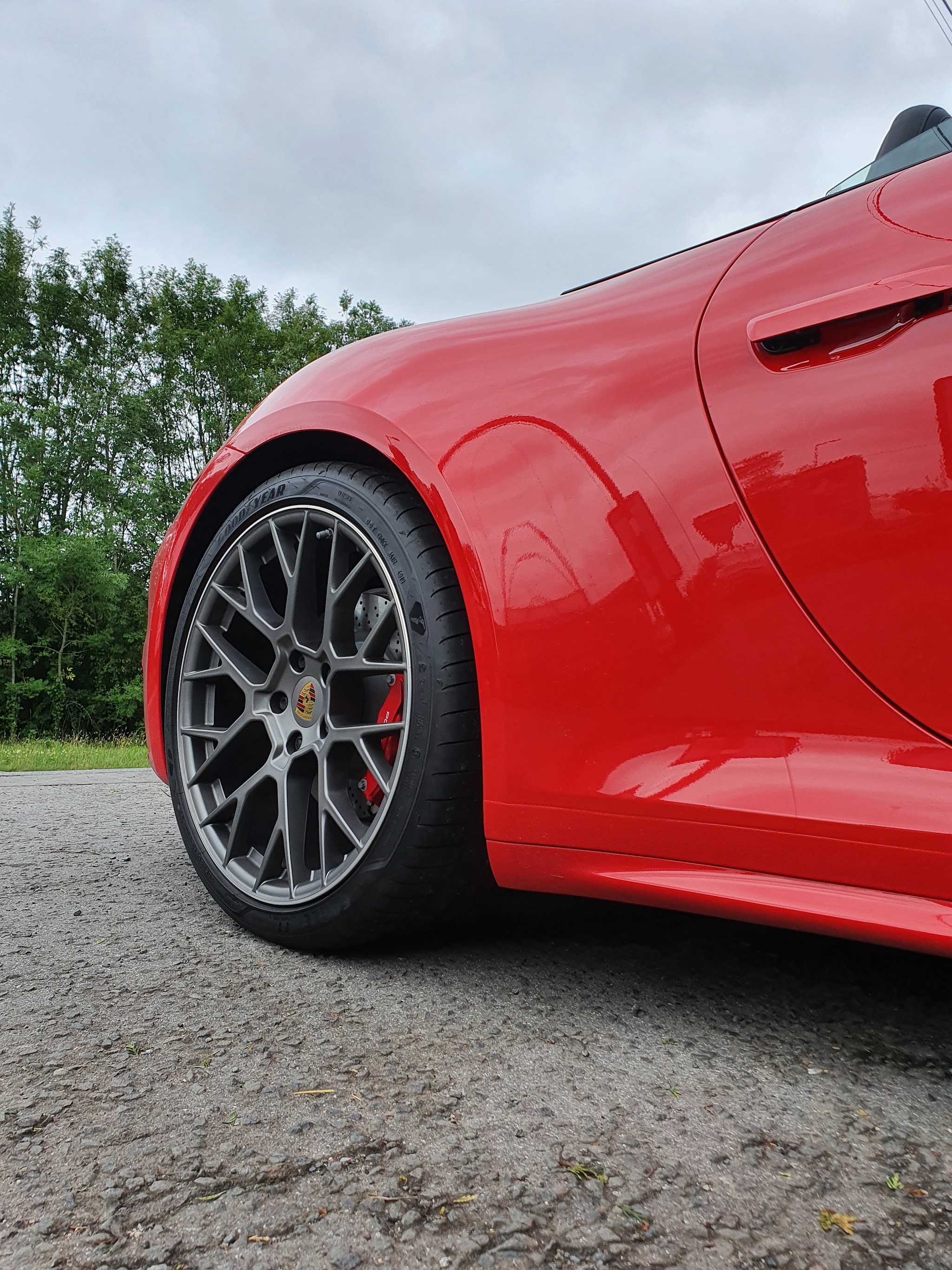 Close-up of a red sports car’s front wing and alloy wheel with a deep gloss finish